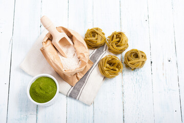 uncooked taglatelle pasta and ingredients: grounded spinach powder and whole wheat flour