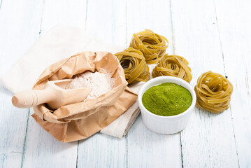 uncooked taglatelle pasta and ingredients: grounded spinach powder and whole wheat flour
