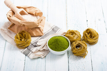 uncooked taglatelle pasta and ingredients: grounded spinach powder and whole wheat flour