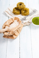 uncooked taglatelle pasta and ingredients: grounded spinach powder and whole wheat flour