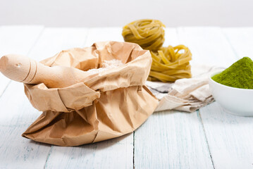 uncooked taglatelle pasta and ingredients: grounded spinach powder and whole wheat flour