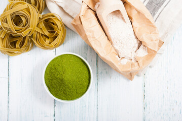 uncooked taglatelle pasta and ingredients: grounded spinach powder and whole wheat flour