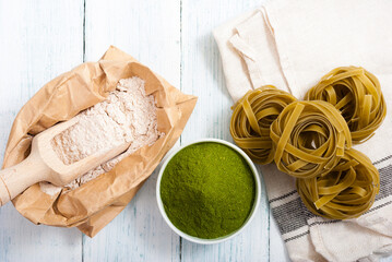 uncooked taglatelle pasta and ingredients: grounded spinach powder and whole wheat flour