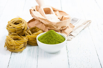 uncooked taglatelle pasta and ingredients: grounded spinach powder and whole wheat flour