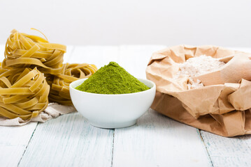 uncooked taglatelle pasta and ingredients: grounded spinach powder and whole wheat flour