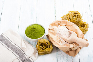 uncooked taglatelle pasta and ingredients: grounded spinach powder and whole wheat flour