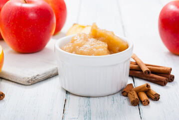 apple jam at porcelain dish, apples, cinnamon, white wood table background