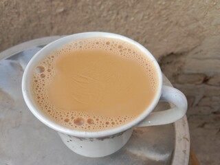 Brown tea in a cup with cheese dome effect on surface showing warm beverage texture and unique food combination in cozy atmosphere closeup view