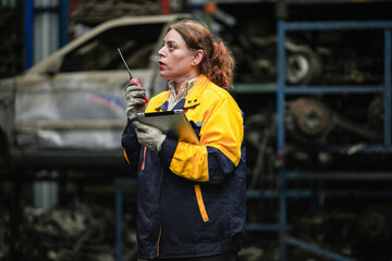Female hispanic technician inspect used car damaged part at scrap yard warehouse recycle area....