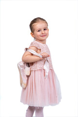 Rear view of a little girl in a pink tutu and ballet slippers, standing gracefully with a tiara on her head, holding pointe shoes.Little ballerina practicing dance moves. 