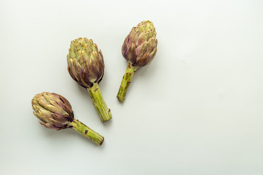 Top view of tree whole heads of purple artichokes. Vegetable ready to cook
