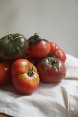 Close up of ripe organic heirloom tomatoes with natural imperfections and vibrant colors on a light fabric background. Healthy farm fresh produce, perfect for vegetarian and vegan food.