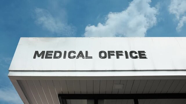 A medical office word sign prominently displayed on a professional building under a clear blue sky, symbolizing primary healthcare, physician services, and appointments