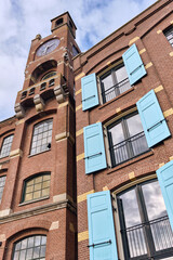 Historic rice factory and warehouse with blue shutters along the Zaan river in Wormer, Netherlands, part of the iconic Zaanwand industrial waterfront redevelopment blending heritage and modern living