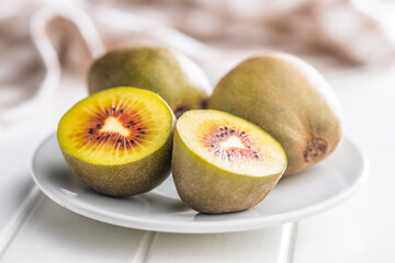 Red kiwi fruit on plate on white table.