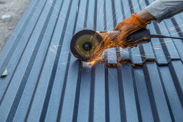 Man is cutting a metal roof with a circular saw. The sparks from the saw are flying everywhere, creating a dangerous and intense scene