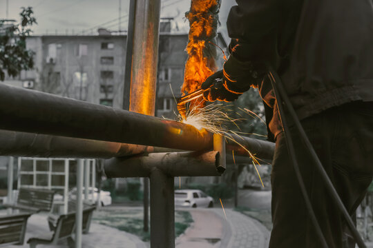 Man is working on a metal structure, using a torch to cut through it - Powered by Adobe