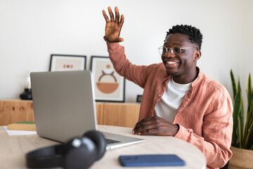 Young man waving goodbye during video call on laptop at home