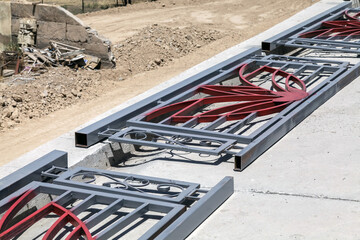 Metal gate with a red flower design is being installed on a sidewalk