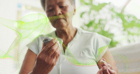 Checking senior woman inspecting blood sugar in living room, with glucose meter and test strip