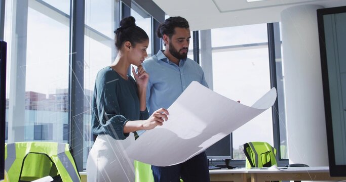 Professional architects unrolling and examining large blueprint in office, with lime-green vests
