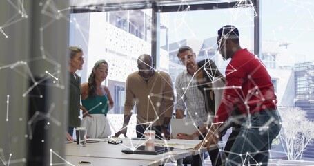 Leaning team examining documents and typing on laptop in conference room with network overlay