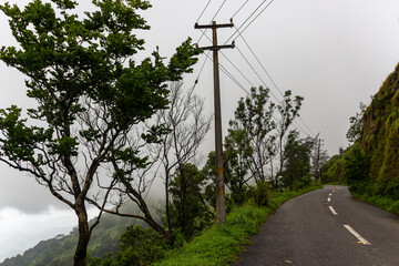 Winding mountain road and utility pole on a cliff edge overlooking a misty valley