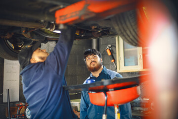 Two mechanics are focused on repairing a vehicle in a garage