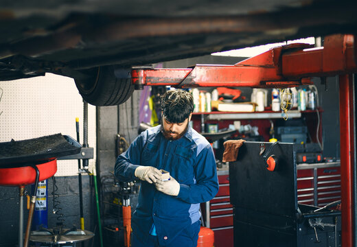 A mechanic is focused on his work under a vehicle in an repair shop