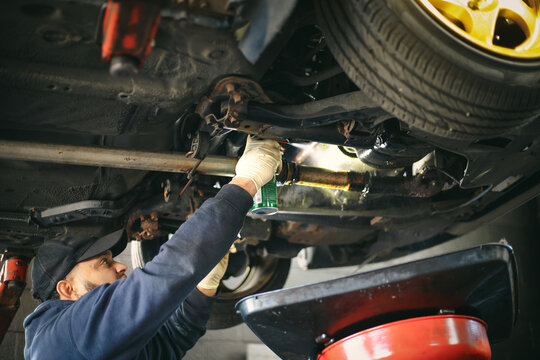 A mechanic can be seen spraying the underside of the car.
