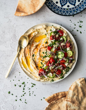 Top view hummus platter with medierranean ingredients and pitas.