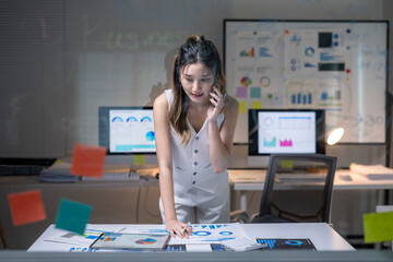 Businesswoman analyzing data graphs working late in office
