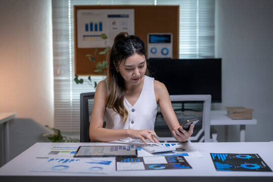 Businesswoman calculating finance data using calculator, smartphone in office - Powered by Adobe