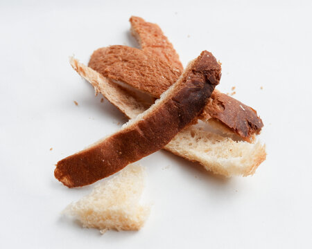 Sad pile of leftover burnt bread crust on white background symbol of food waste and overcooked breakfast toast showing dry discarded brown and black snack - Powered by Adobe
