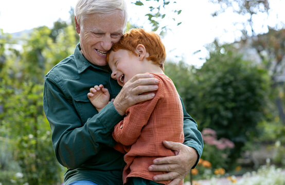 Happy grandfather embracing grandson in park