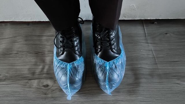 Shoe covers are worn on black shoes on women's feet. Disposable Medical Blue Shoe Covers For Walking Indoors, Hospital