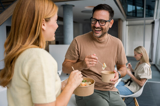 Colleagues enjoying healthy lunch break and talking at modern office