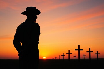 Anzac Digger silhouette stands solemnly during a poignant sunrise, honoring sacrifice amidst a field of memorial crosses under a vibrant sky