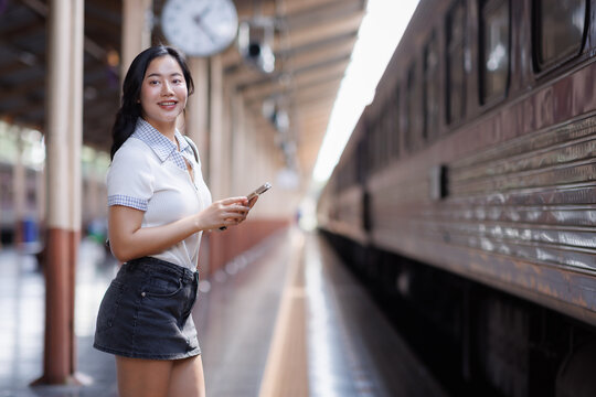 Young asian woman traveling by train using smartphone
