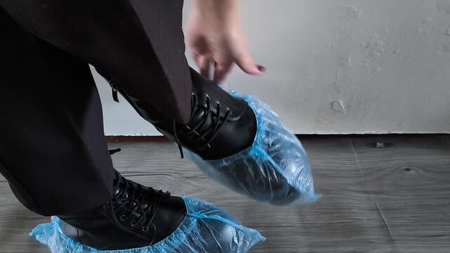 A woman removes shoe covers from shoes on her feet. Disposable, medical shoe covers