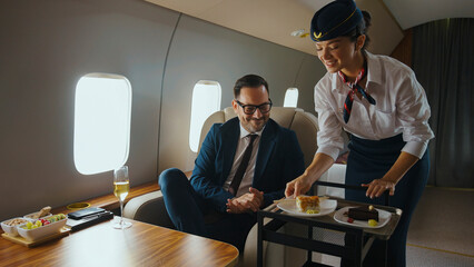 Flight attendant serving elegant desserts to a smiling businessman enjoying luxury service and...