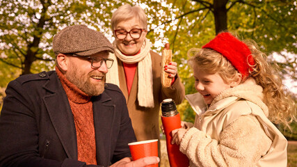 Father laughing as daughter pours tea under grandmother smile. Concept of joyful family learning, warmth, and connection for social, educational, and lifestyle visuals.
