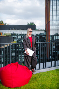 Businesswoman with laptop outdoors on modern rooftop mentions remote work