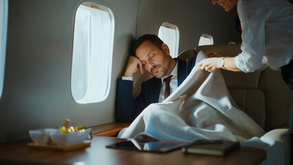 Flight attendant gently covering a businessman sleeping comfortably in a seat on a luxurious private jet, symbolizing comfort, executive travel, and premium passenger service