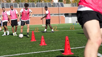 Soccer players training with cones on artificial grass field - Powered by Adobe