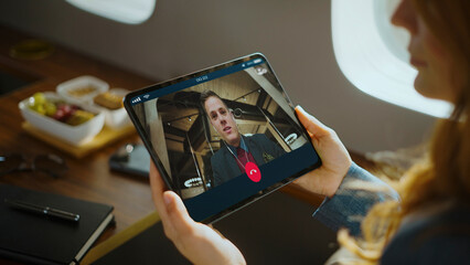 Professional woman enjoying luxury travel on a private jet, staying connected with a video call on a modern foldable smartphone, discussing business while flying