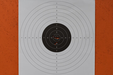 Precision shooting results on a paper target, with bullet holes grouped tightly in the 9 and 10...