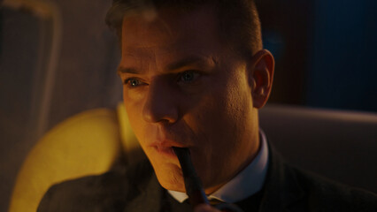 Close-up on a pensive man wearing a vintage suit and smoking a pipe, illuminated by dramatic light, creating an atmosphere of deep thought, contemplation, and mystery