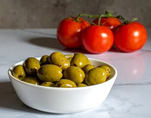 Close-up of green olives in a bowl, with ripe tomatoes in the background