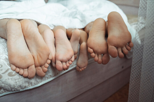 Family lying under blanket on bed at home